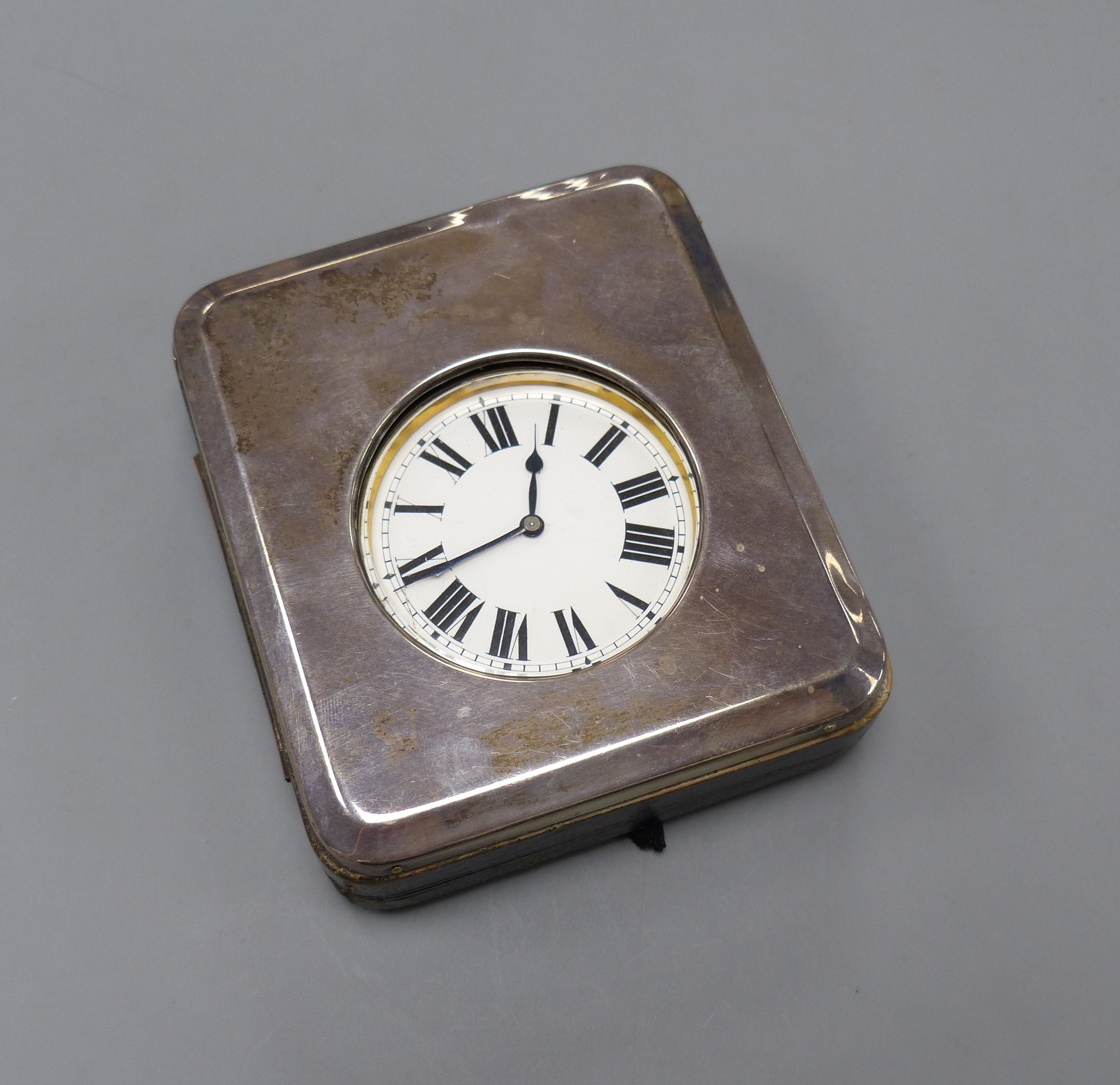A George V silver mounted travelling watch case, with an incomplete nickel cased pocket watch, 11.2cm.